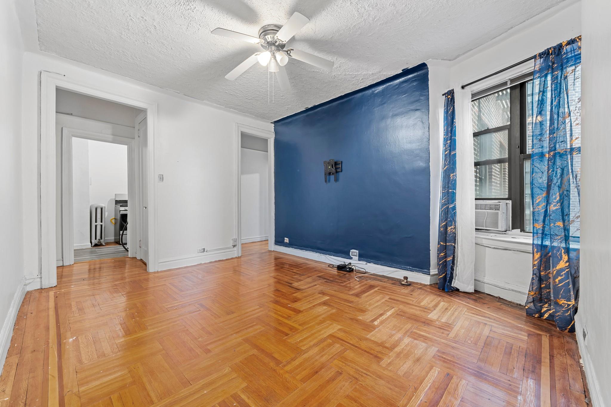 Empty room featuring ceiling fan, cooling unit, parquet floors, and a textured ceiling