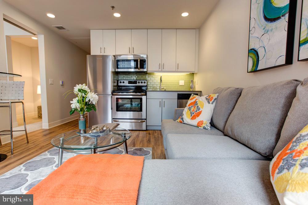 a living room with stainless steel appliances furniture and a kitchen view