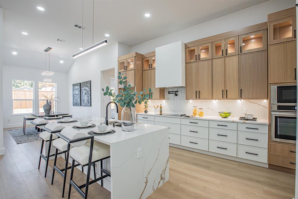 a kitchen with stainless steel appliances kitchen island granite countertop a table chairs sink and cabinets