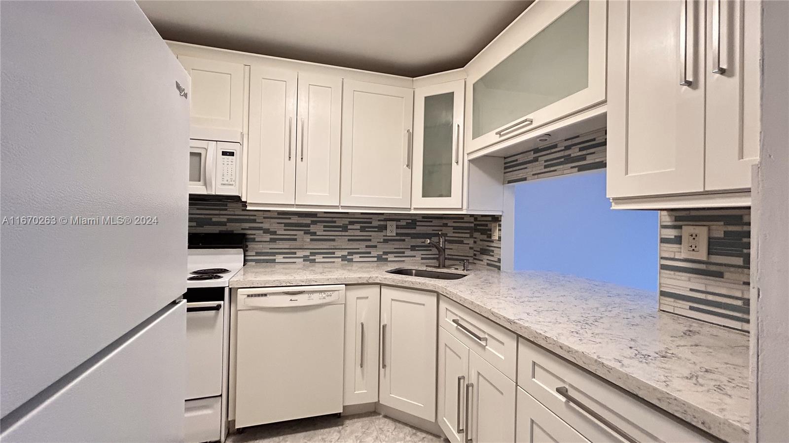 a kitchen with granite countertop white cabinets and white appliances