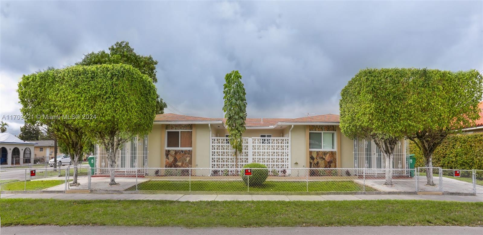 a front view of a house with a garden and trees