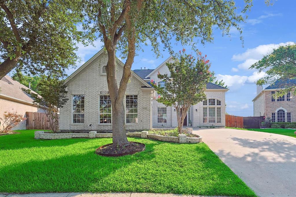 a front view of a house with garden and trees