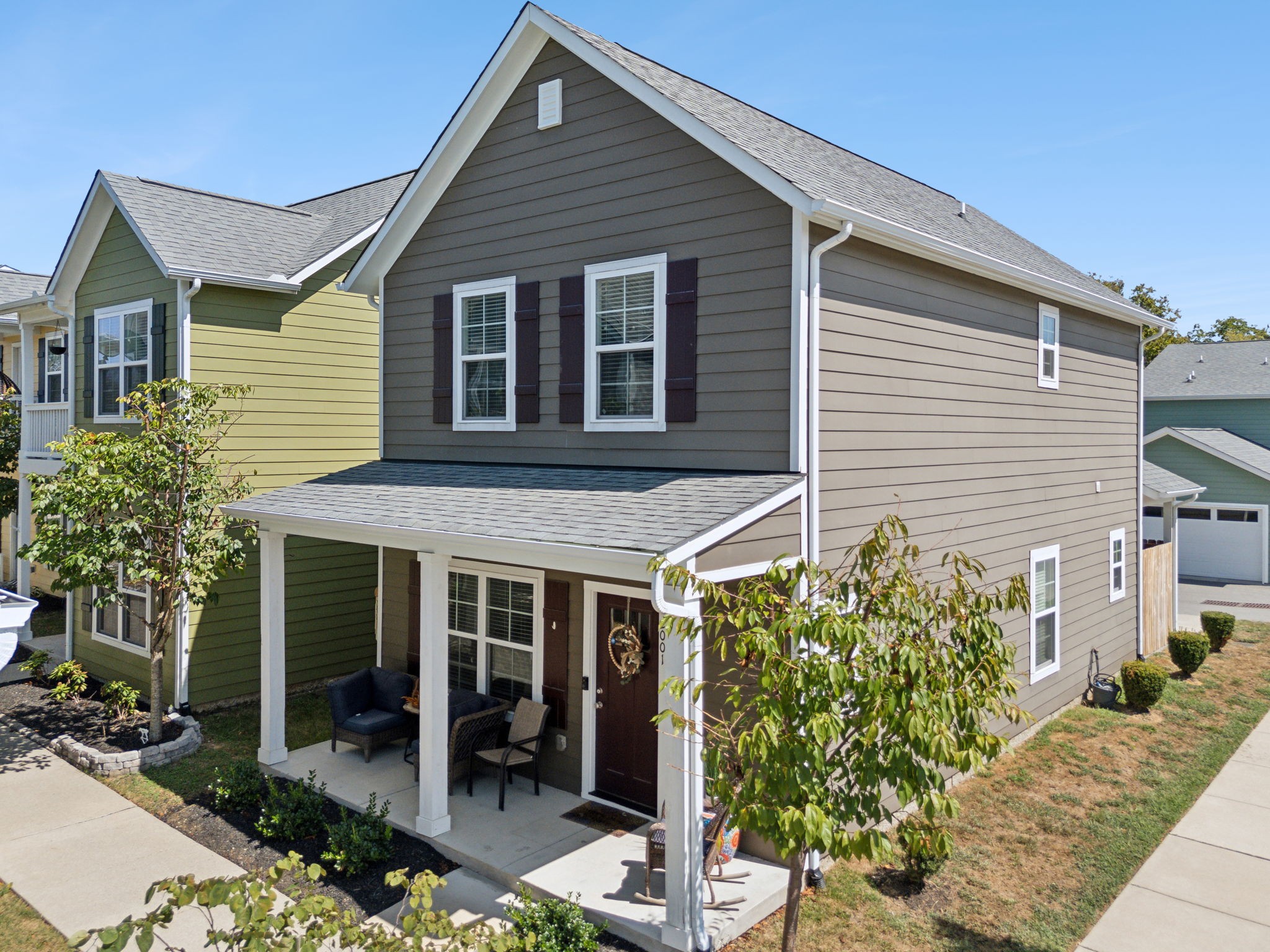 “Charming two-story home with taupe siding, white trim, and a cozy porch—perfect for relaxation and neighborhood views.”