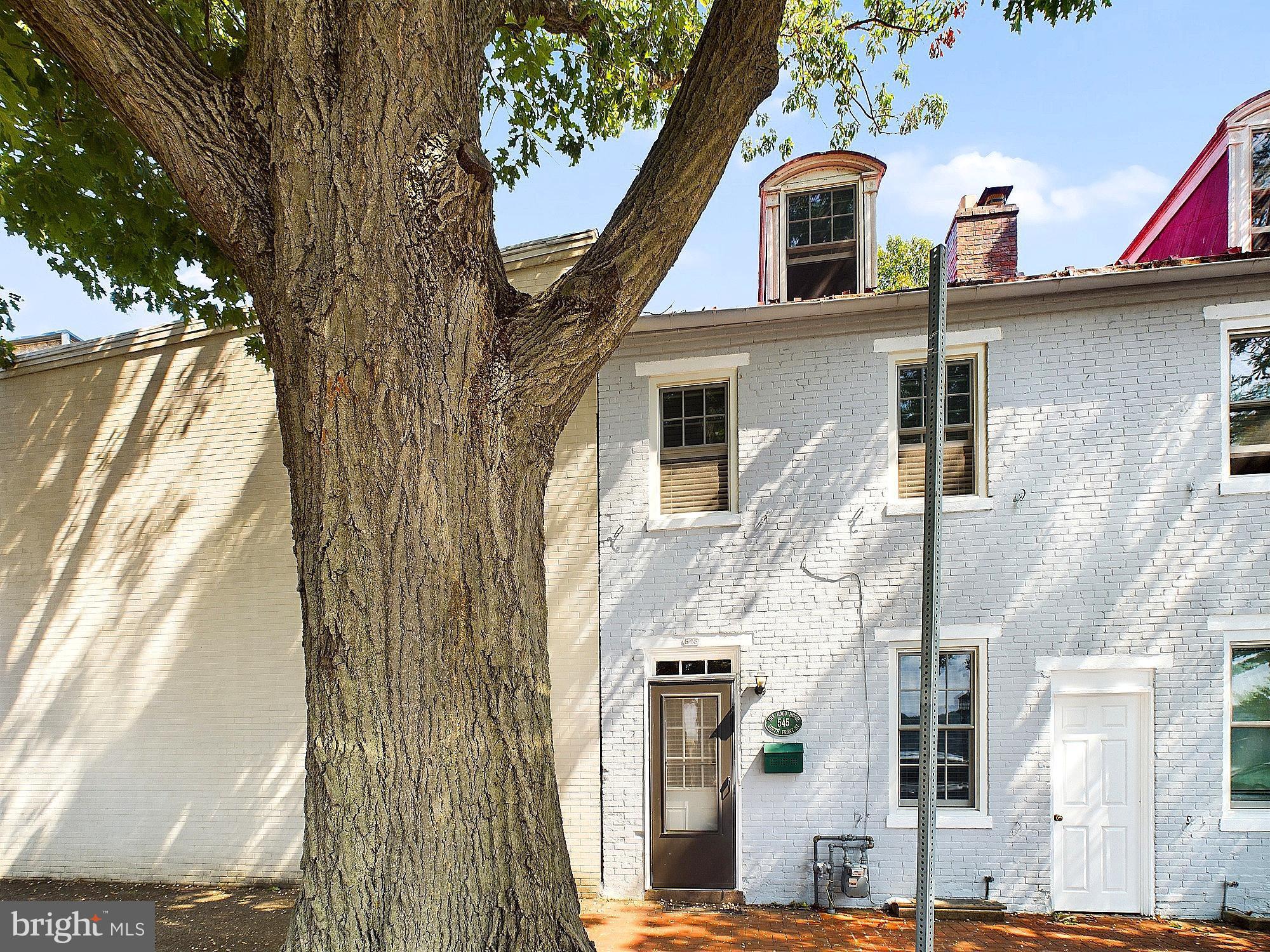 a front view of a house with large trees