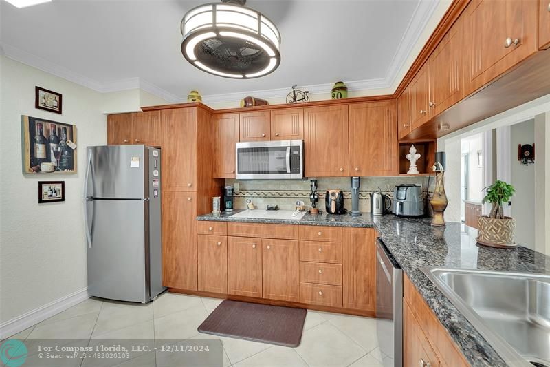 a kitchen with stainless steel appliances granite countertop a refrigerator a stove a sink and a microwave