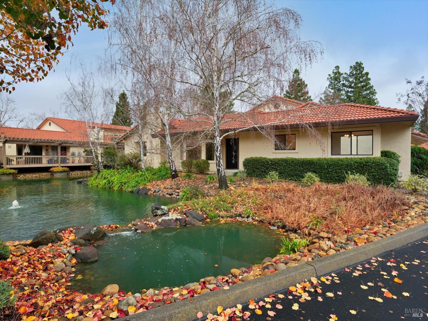 a front view of a house with a garden and lake view