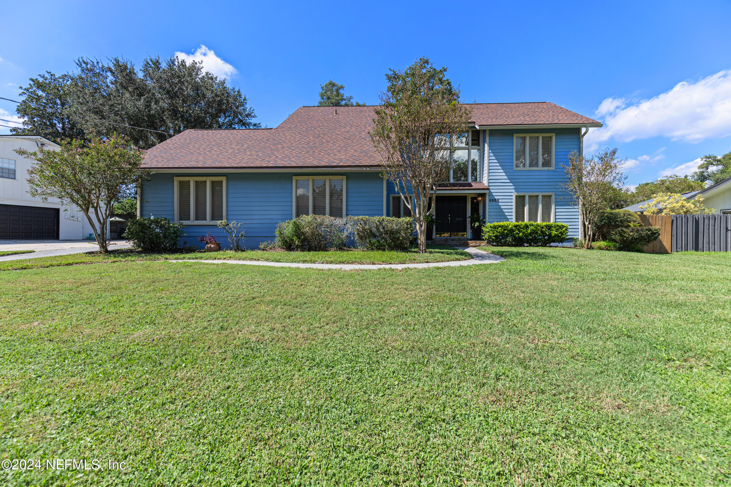 a front view of a house with a garden and trees