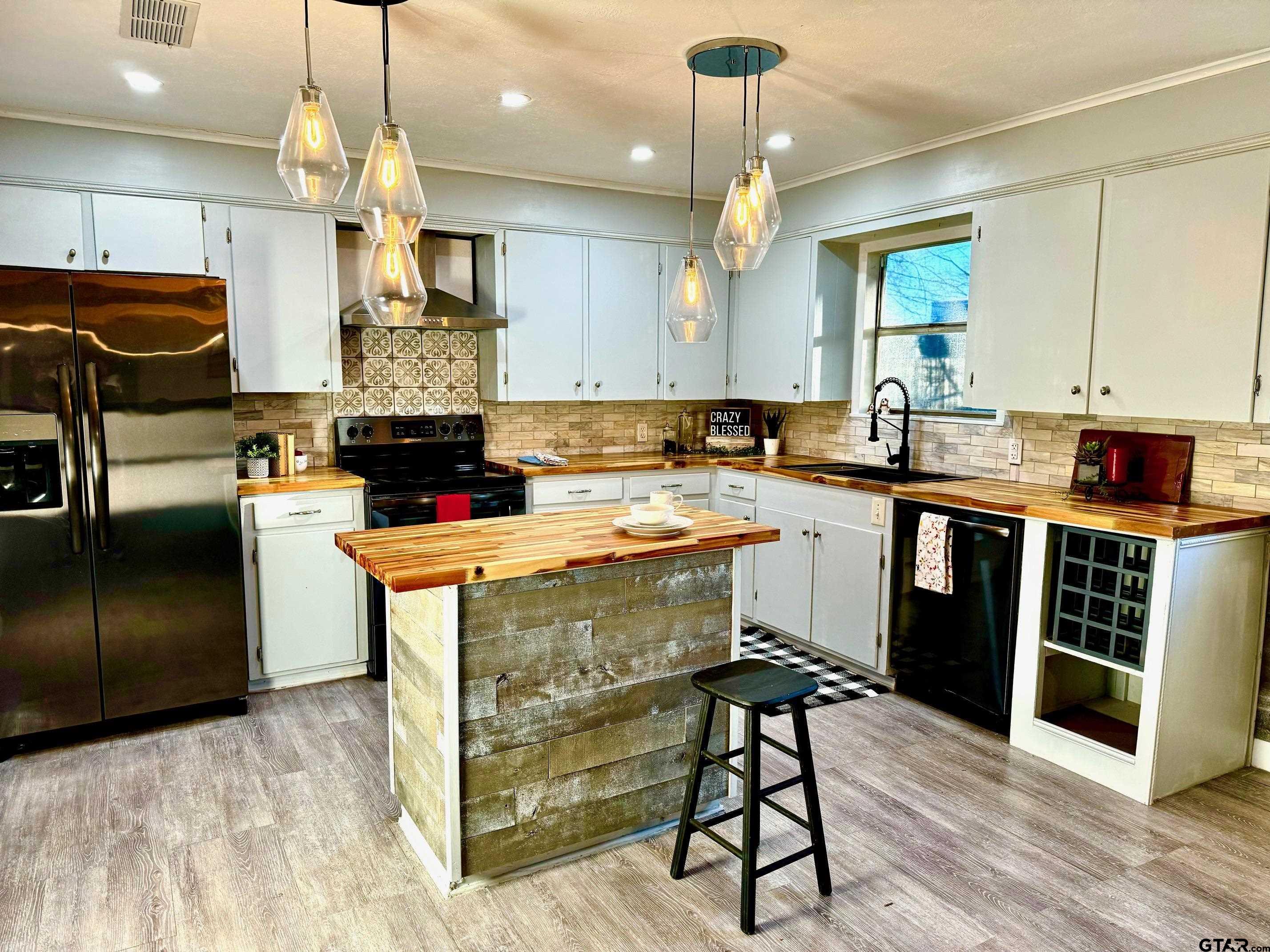 a kitchen with kitchen island granite countertop a sink a counter top space stainless steel appliances and cabinets