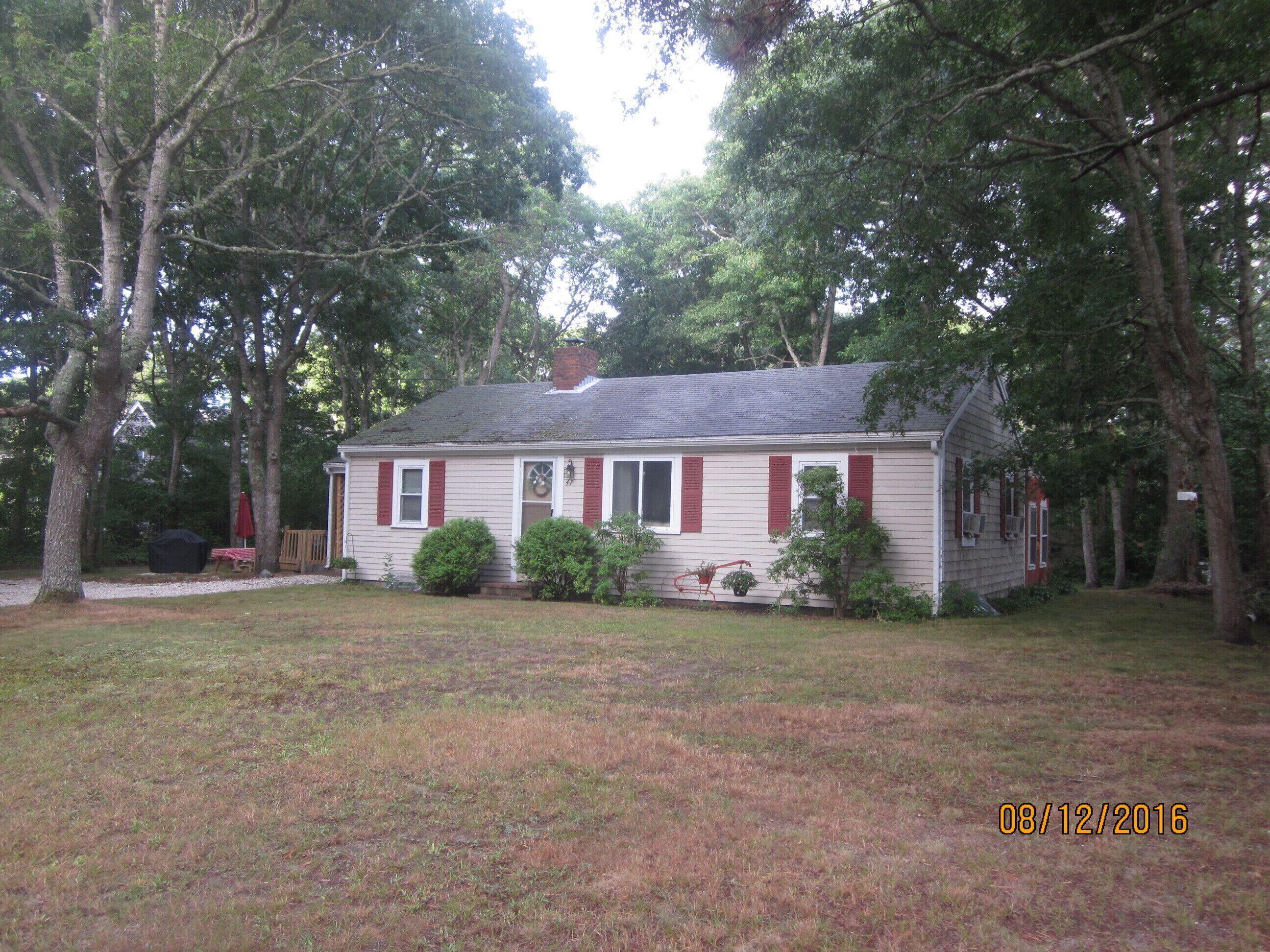 a view of a yard in front of a house with large trees