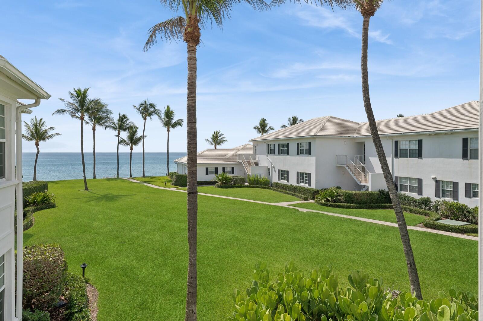 a view of a house with a big yard and palm trees