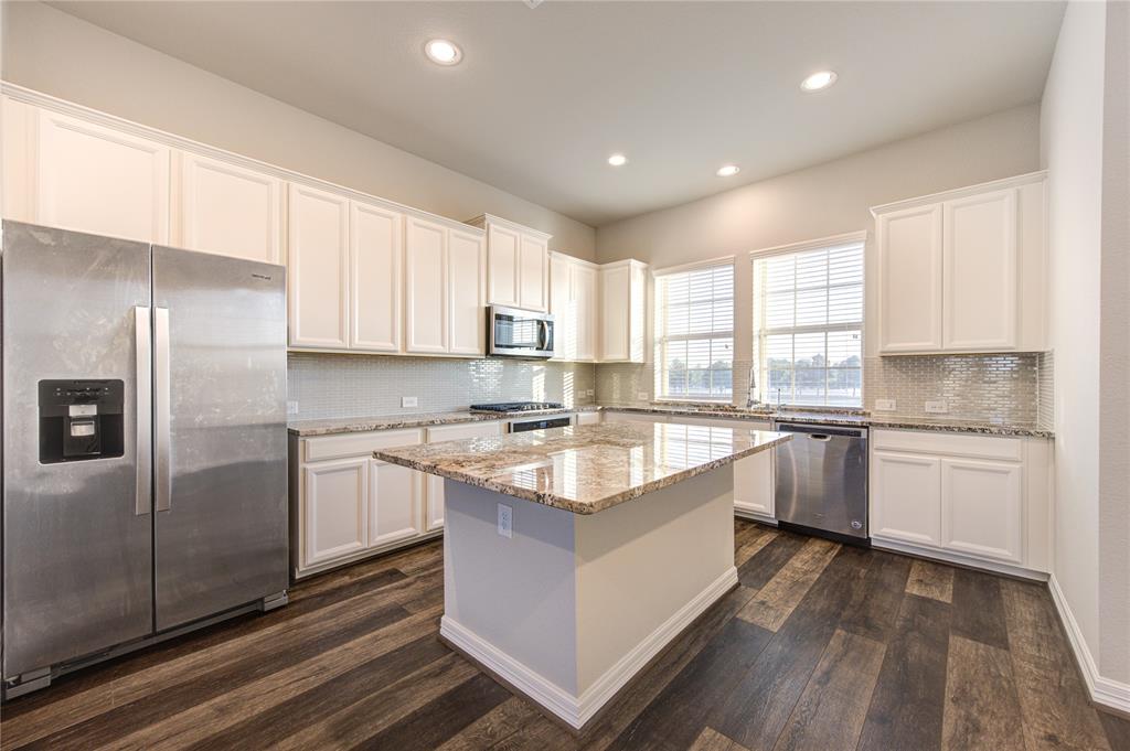 a large kitchen with stainless steel appliances granite countertop a stove a sink dishwasher and a refrigerator