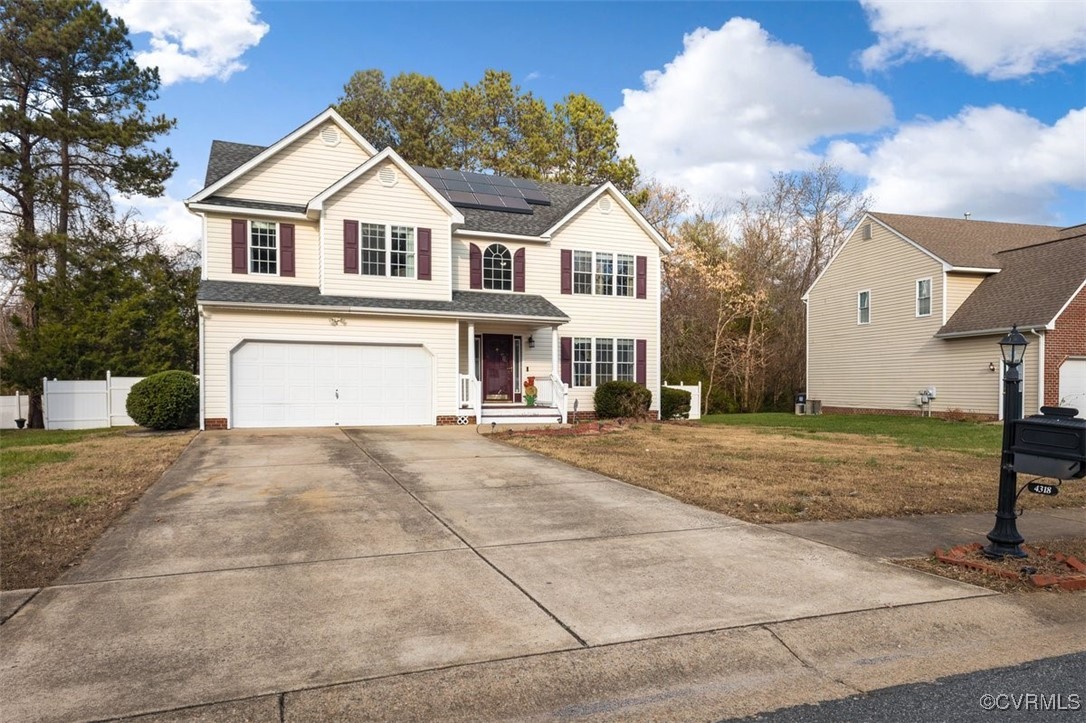 View of property with solar panels, a garage, and