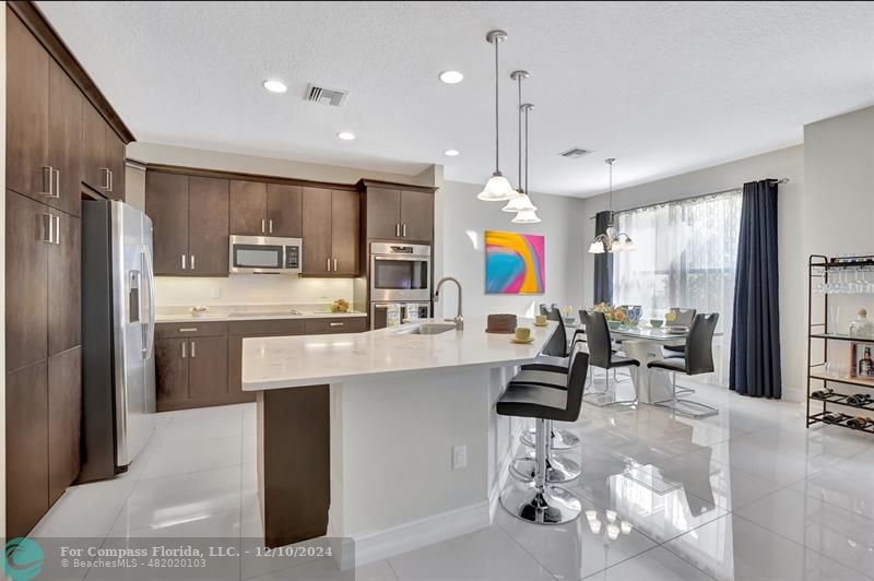 a kitchen with stainless steel appliances kitchen island granite countertop a sink refrigerator and cabinets