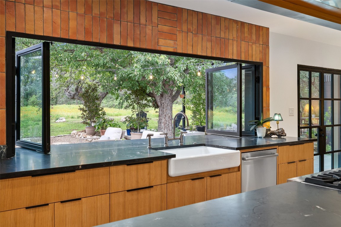 a kitchen with stainless steel appliances wooden cabinets a sink and a large window