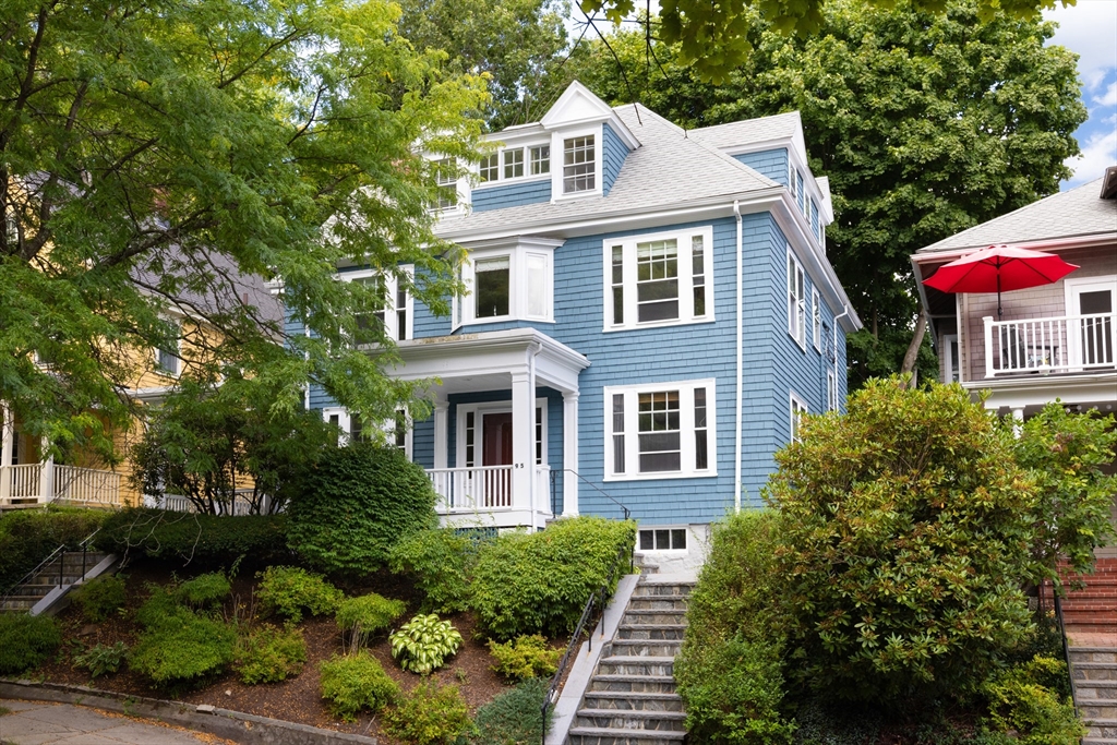 a front view of a house with plants and trees