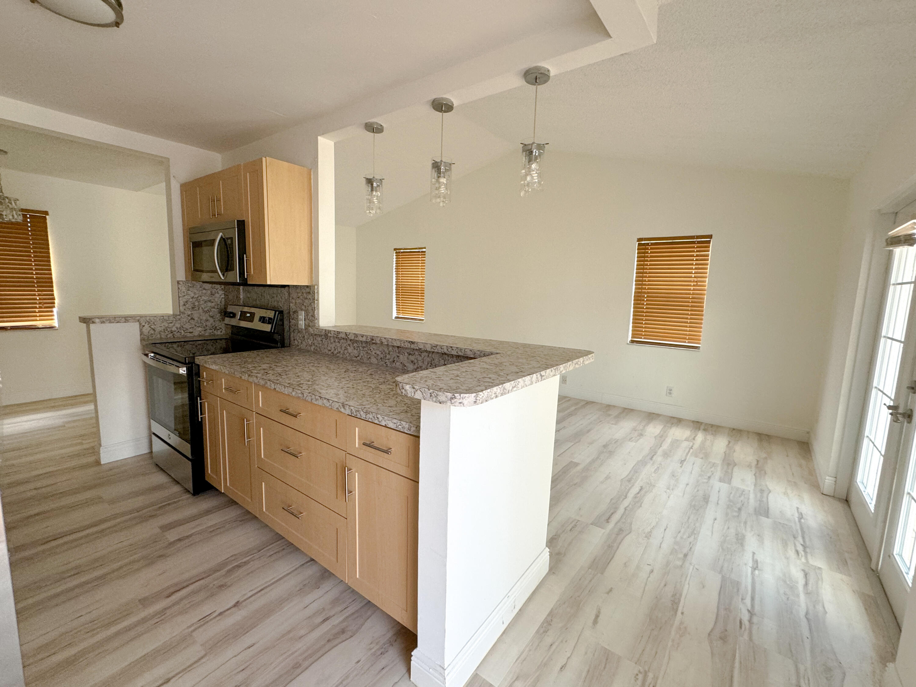 a kitchen with granite countertop a sink cabinets wooden floor and stainless steel appliances