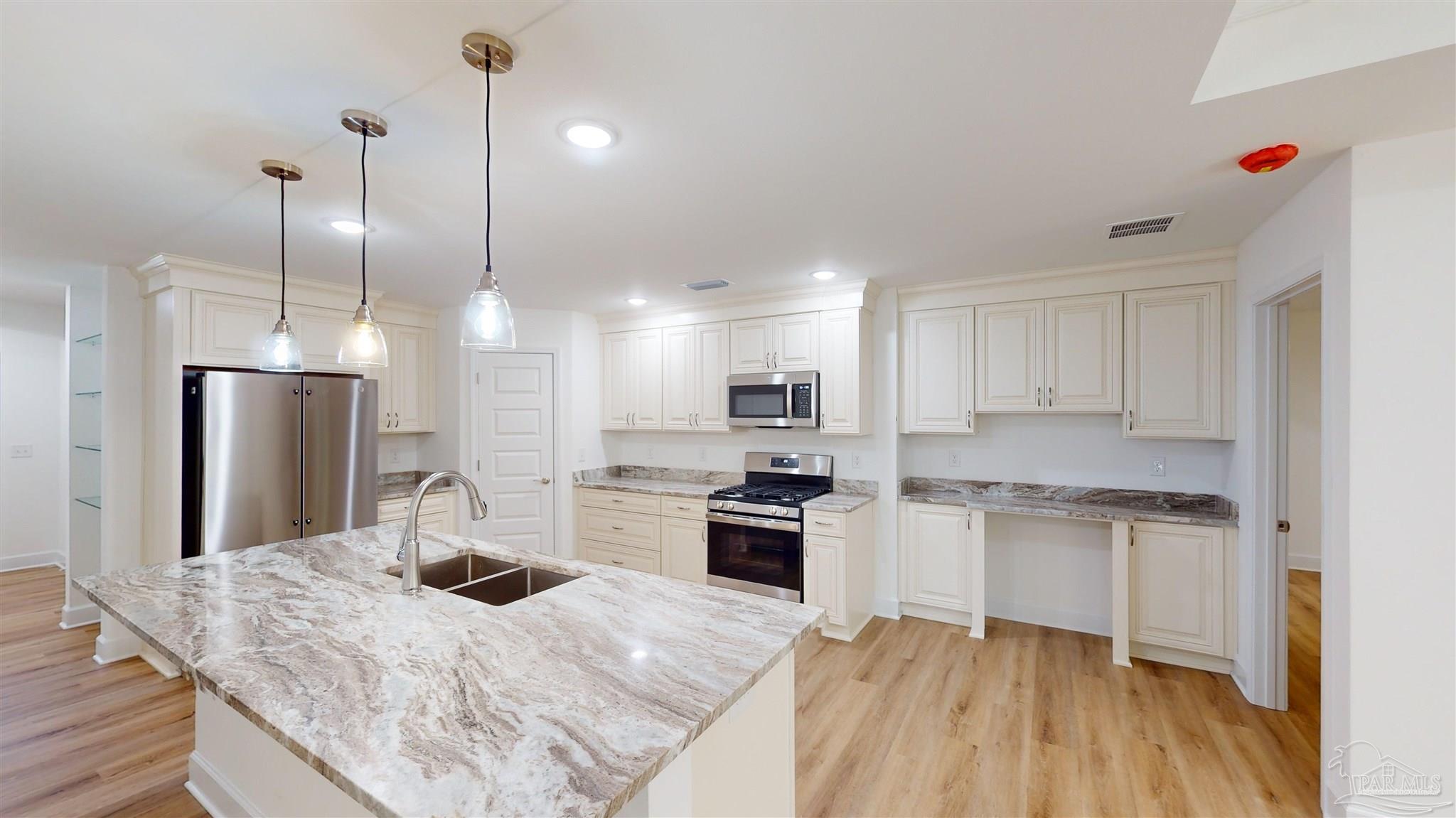 a kitchen with kitchen island a sink stainless steel appliances and white cabinets