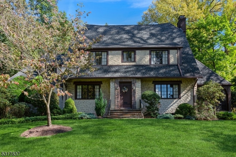 a view of a brick house with a big yard and large trees