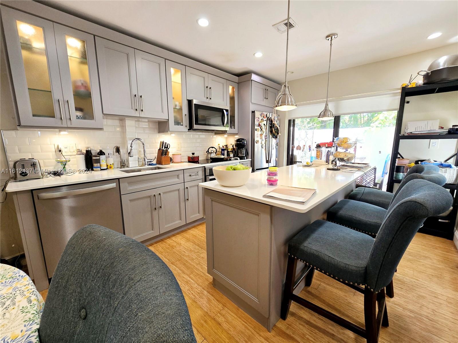 a kitchen with stainless steel appliances granite countertop a sink a stove a refrigerator a dining table and chairs