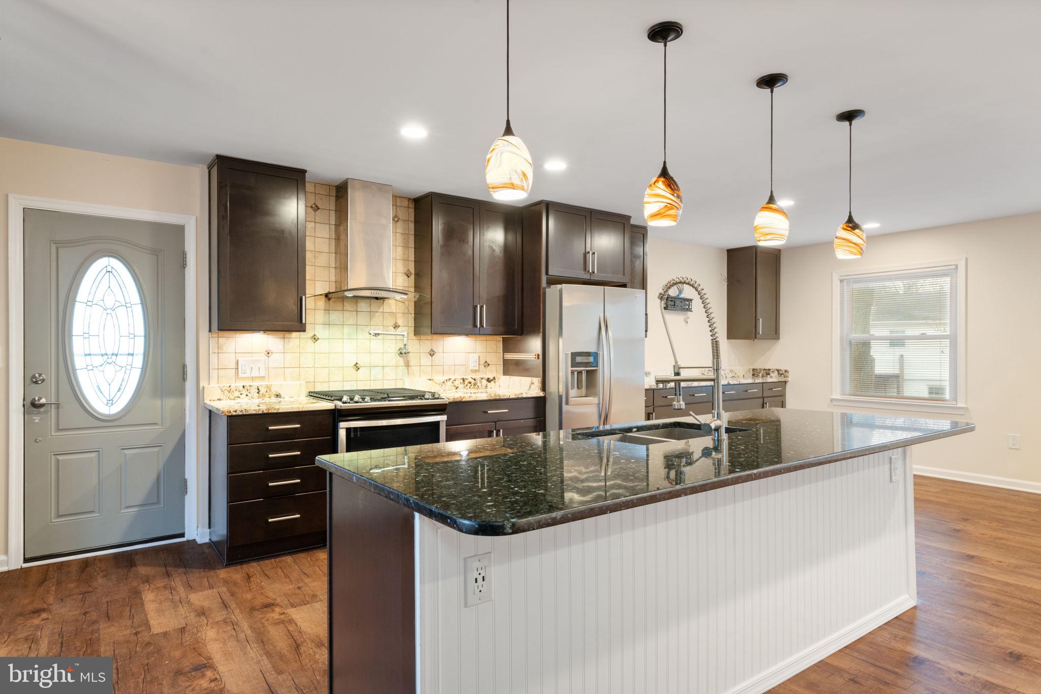 a kitchen with stainless steel appliances granite countertop a sink a stove and a wooden floors