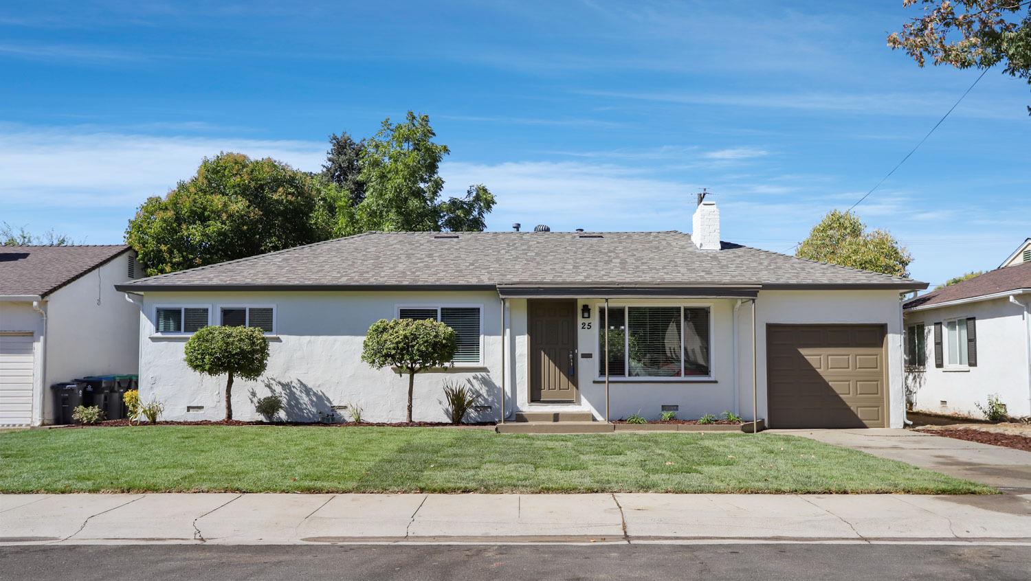 a front view of a house with a yard and potted plants