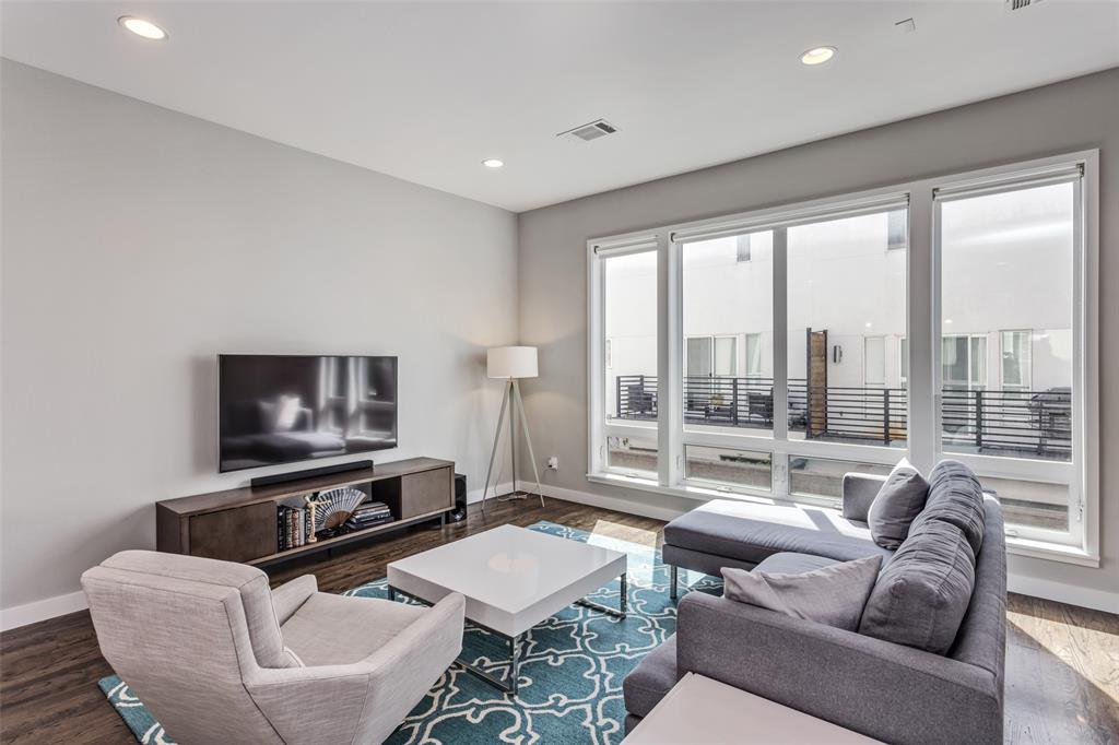 a living room with furniture a flat screen tv and a floor to ceiling window