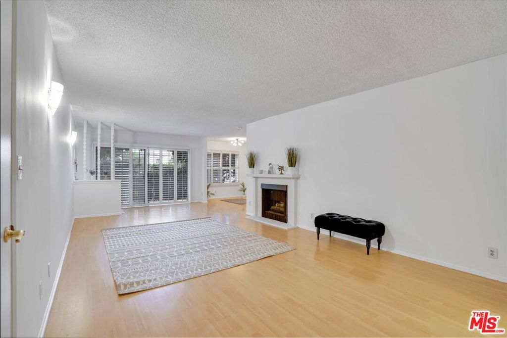 a view of an empty room with wooden floor and a fireplace