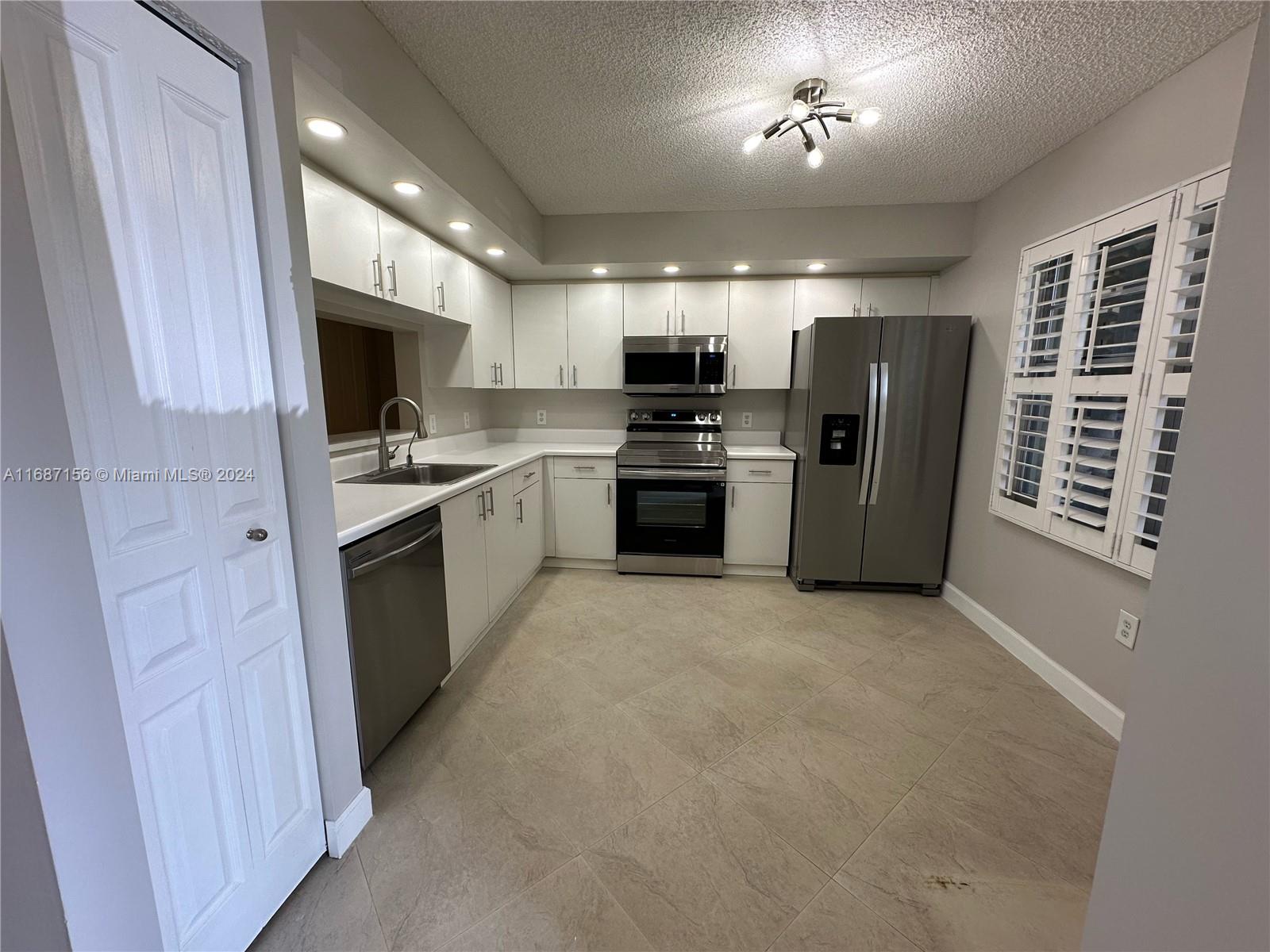 a kitchen with stainless steel appliances granite countertop a refrigerator stove and sink