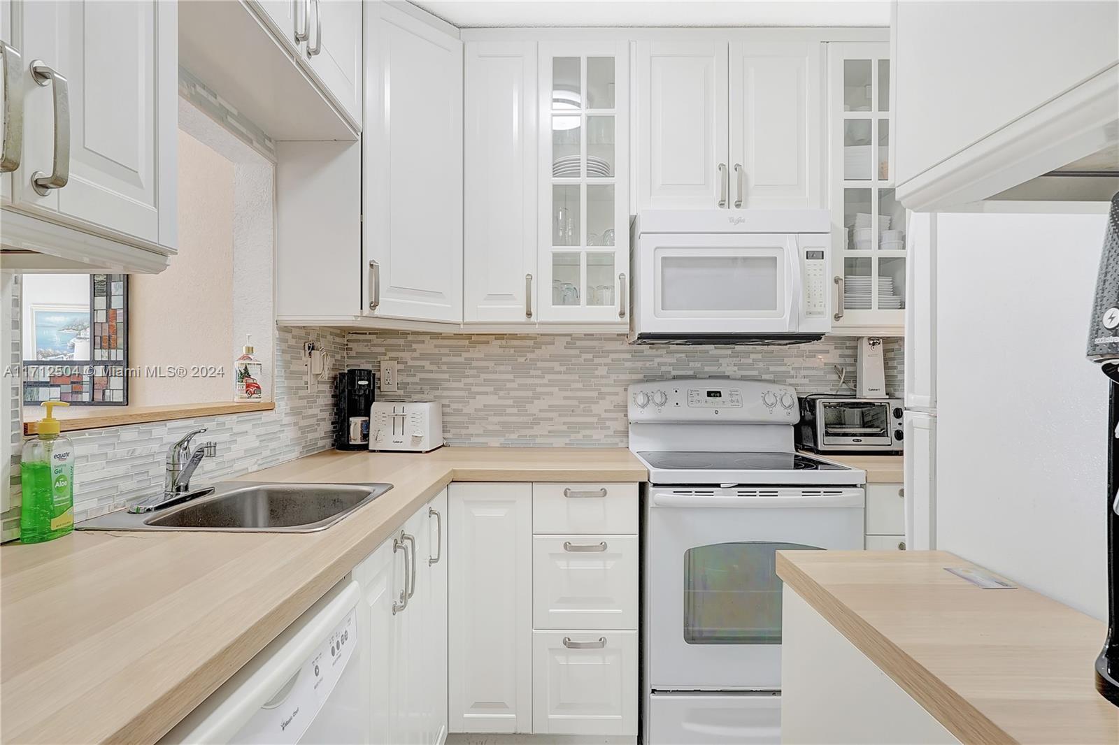 a kitchen with white cabinets white stainless steel appliances and sink