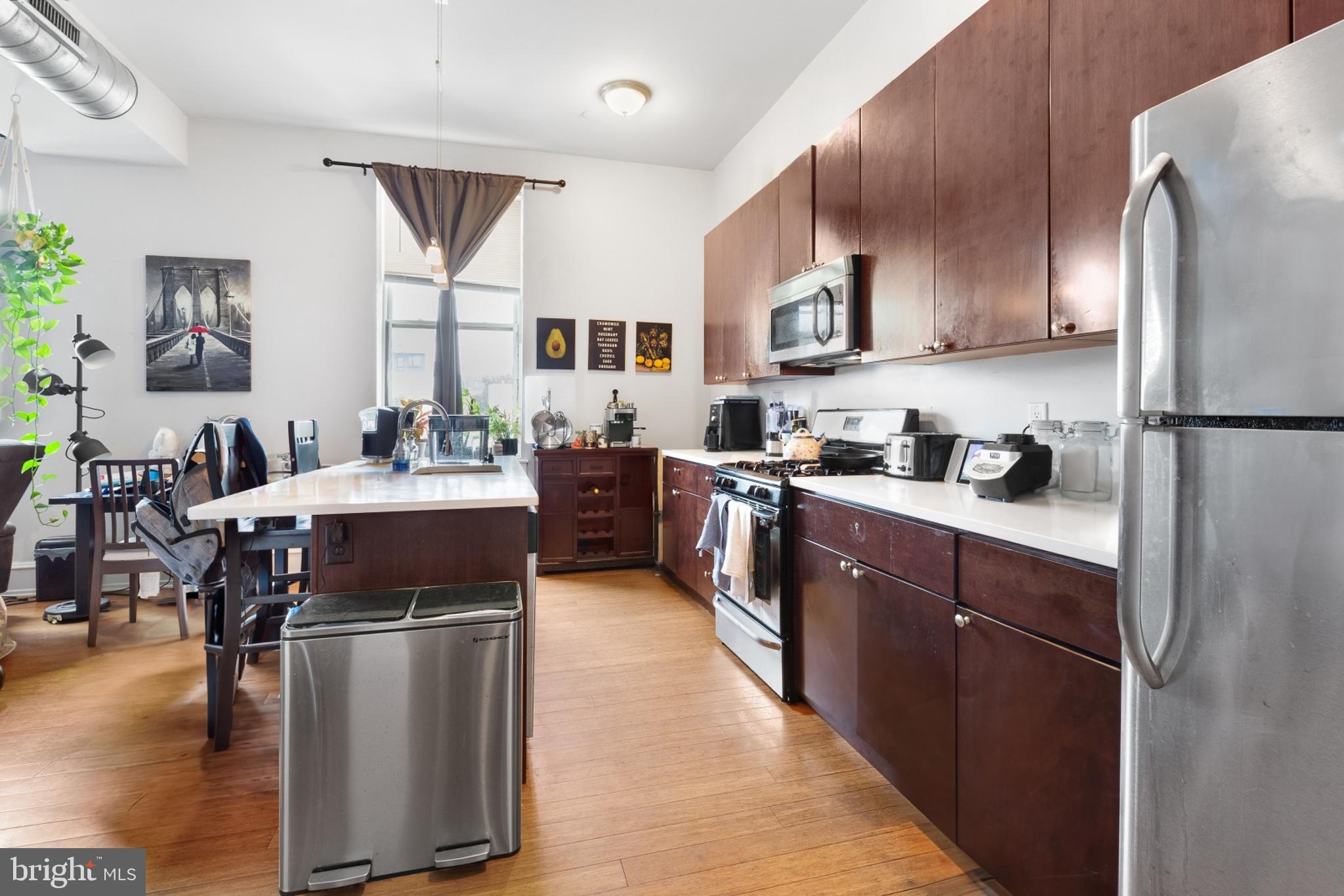 a kitchen with stainless steel appliances kitchen island granite countertop a refrigerator a sink dishwasher a stove with wooden cabinets and floor