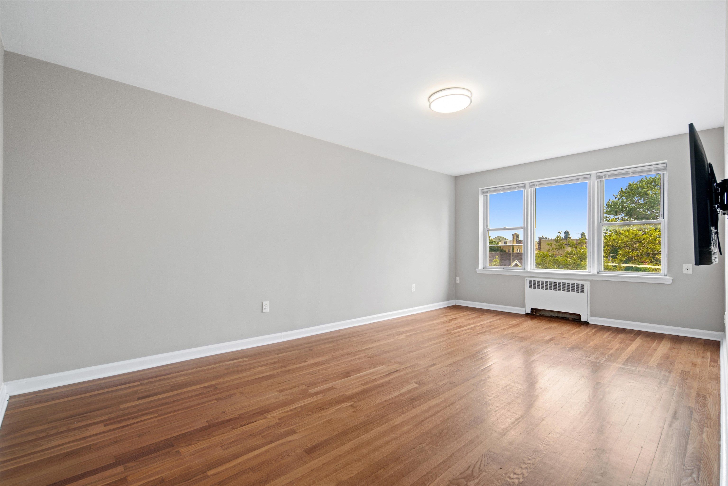 a view of an empty room with a window and wooden floor