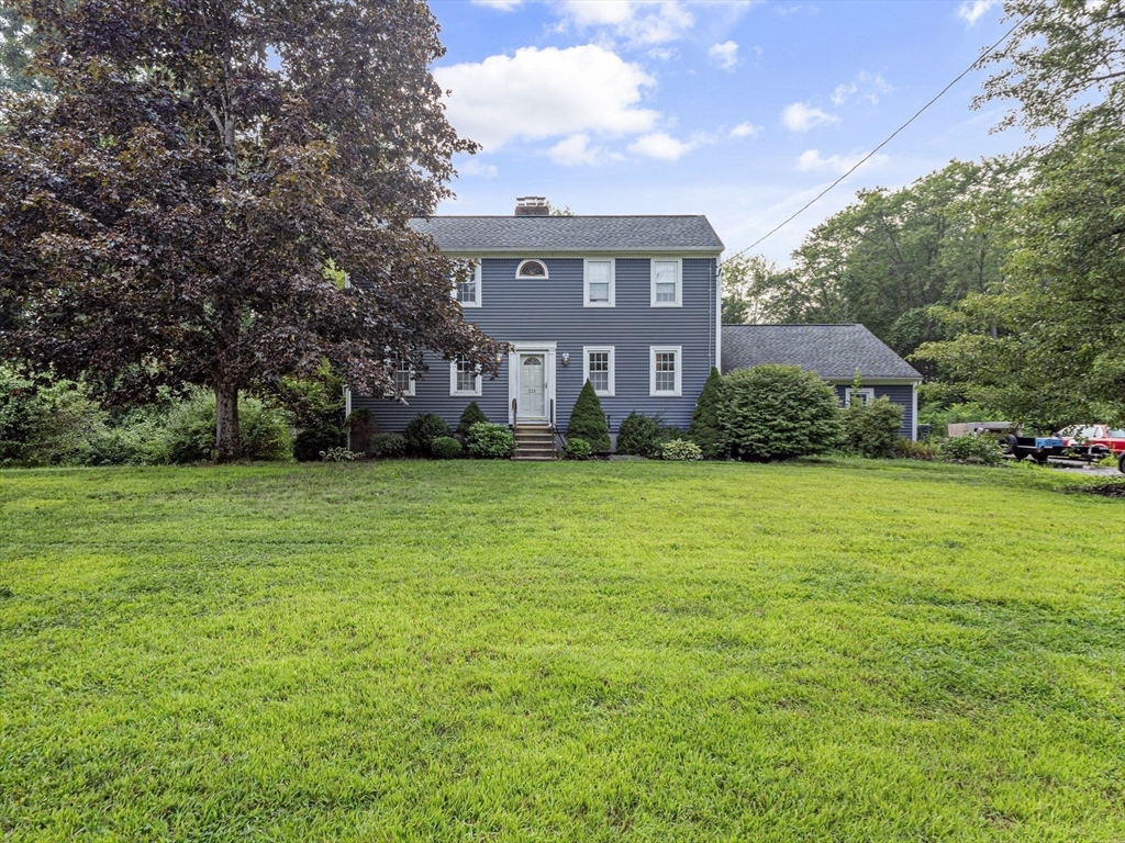 a view of house in front of a big yard with large trees