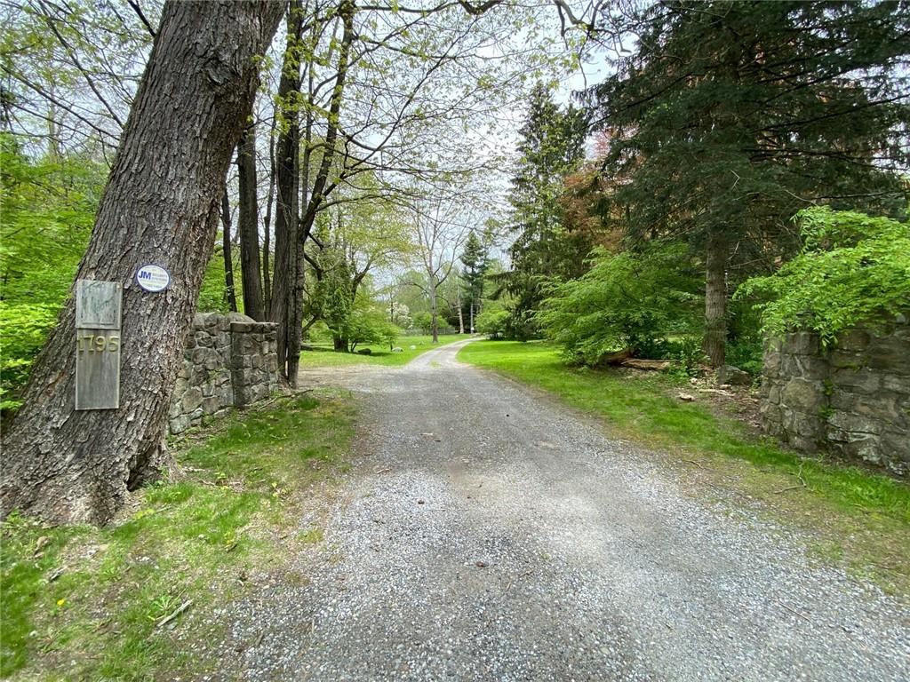 Stone walls welcome the gravel road to the home.