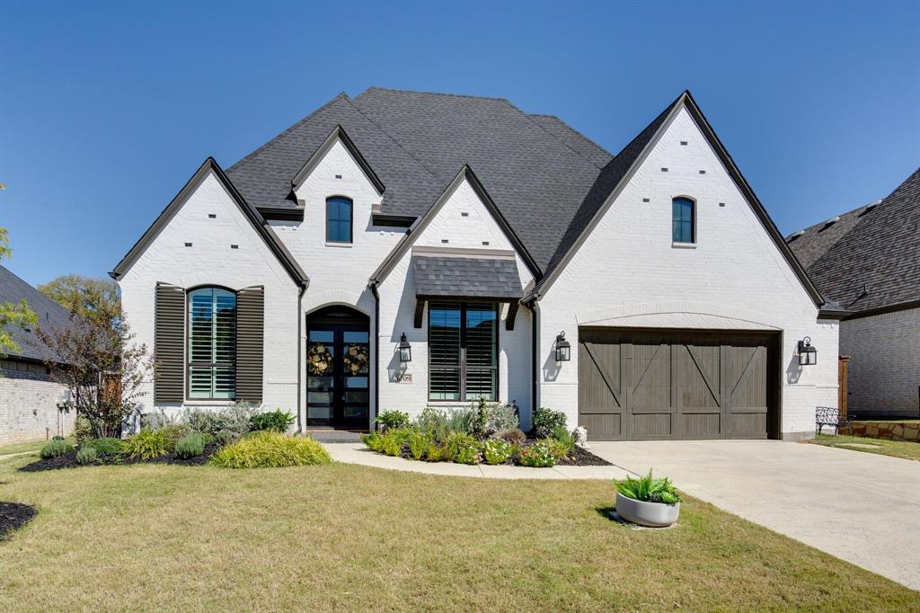 French country inspired facade with a front lawn and a garage