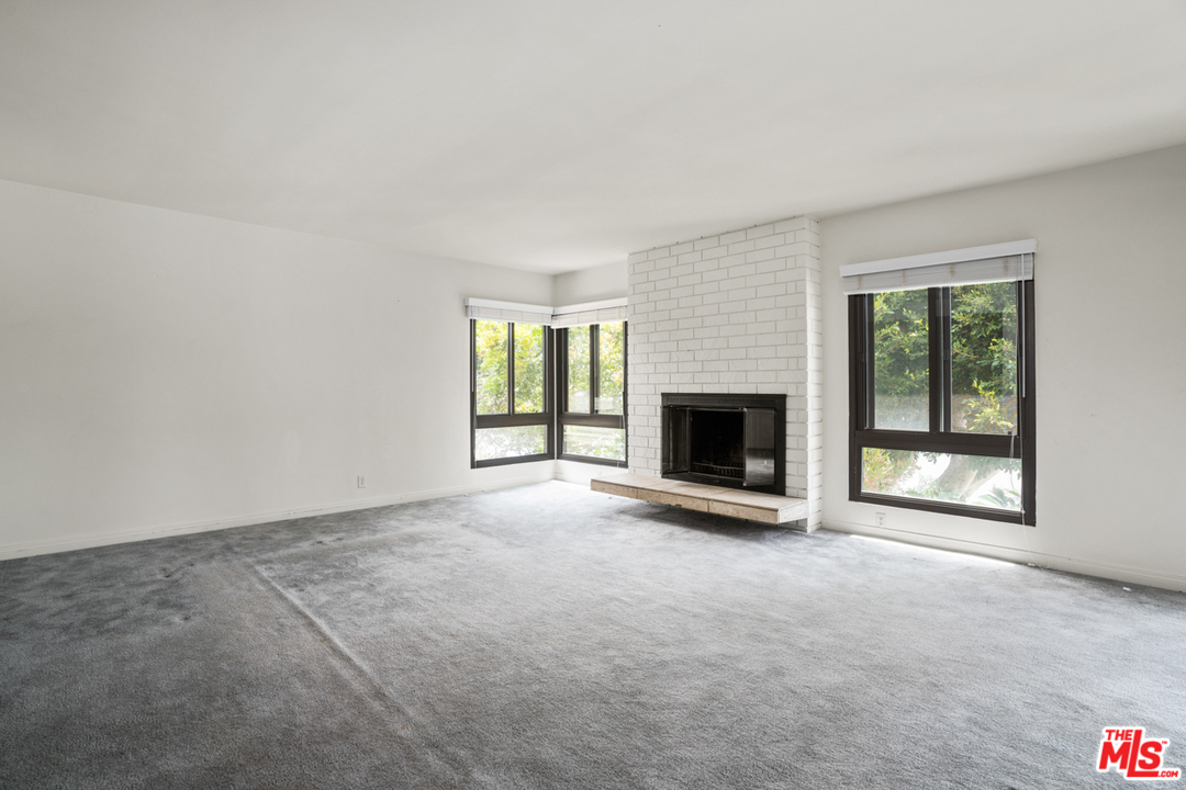 an empty room with floor to ceiling window and fireplace