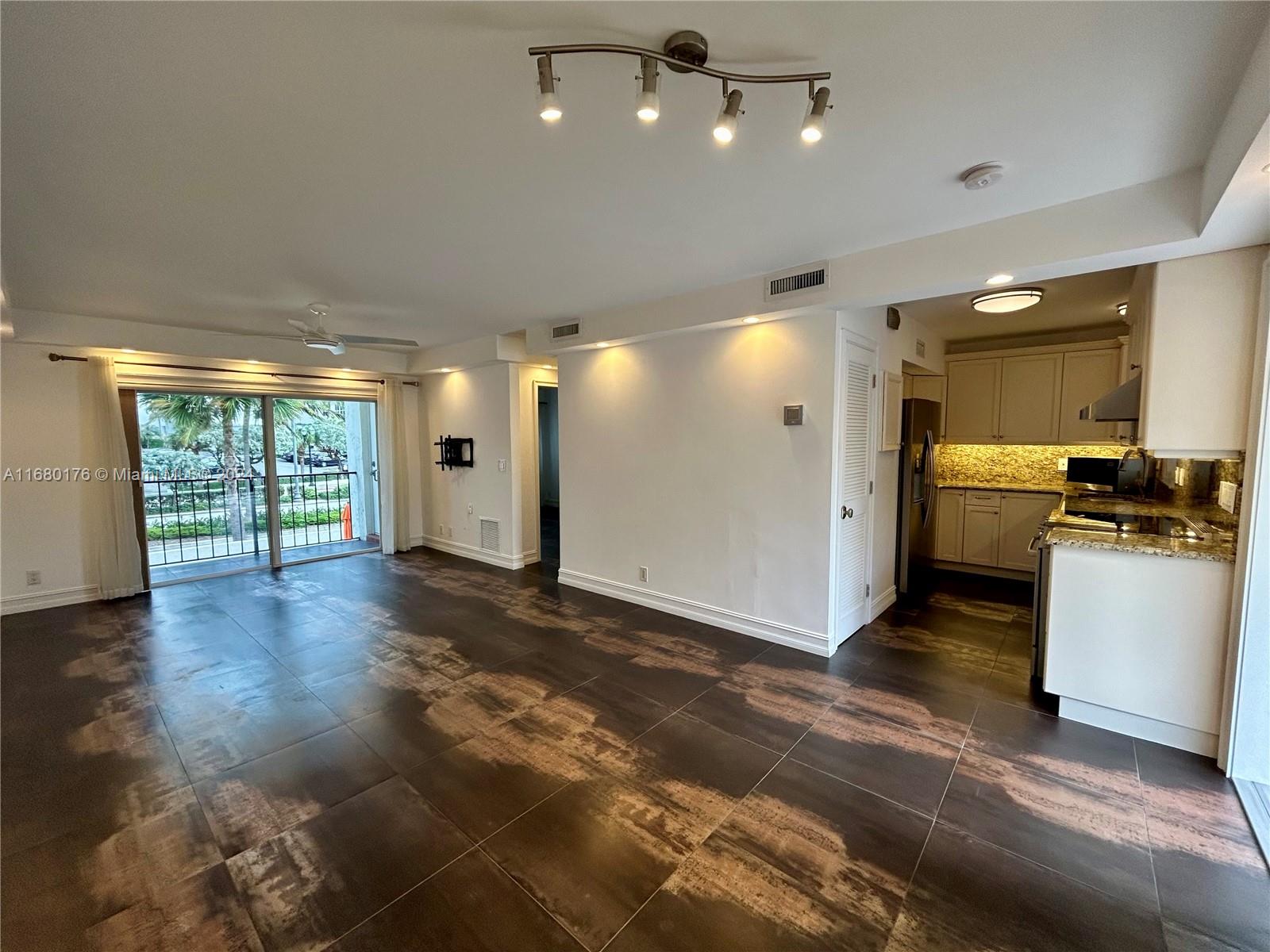 a view of a electric appliances in kitchen and empty room with wooden floor