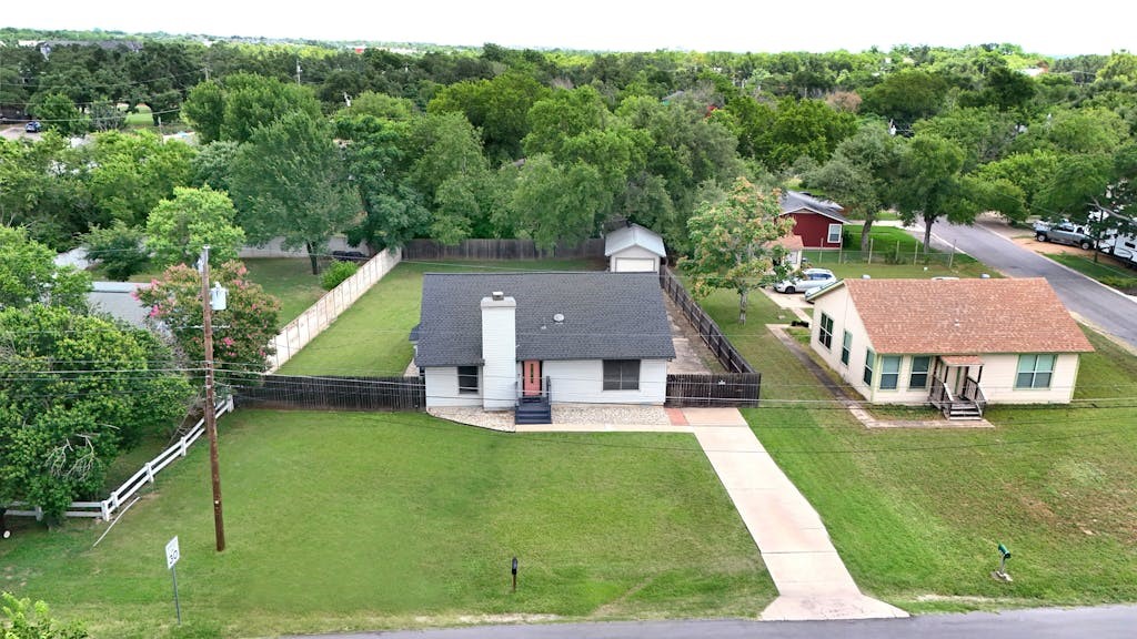 an aerial view of a house with swimming pool garden and tall trees