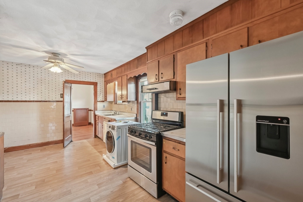 a kitchen with stainless steel appliances a refrigerator a stove a sink and white cabinets