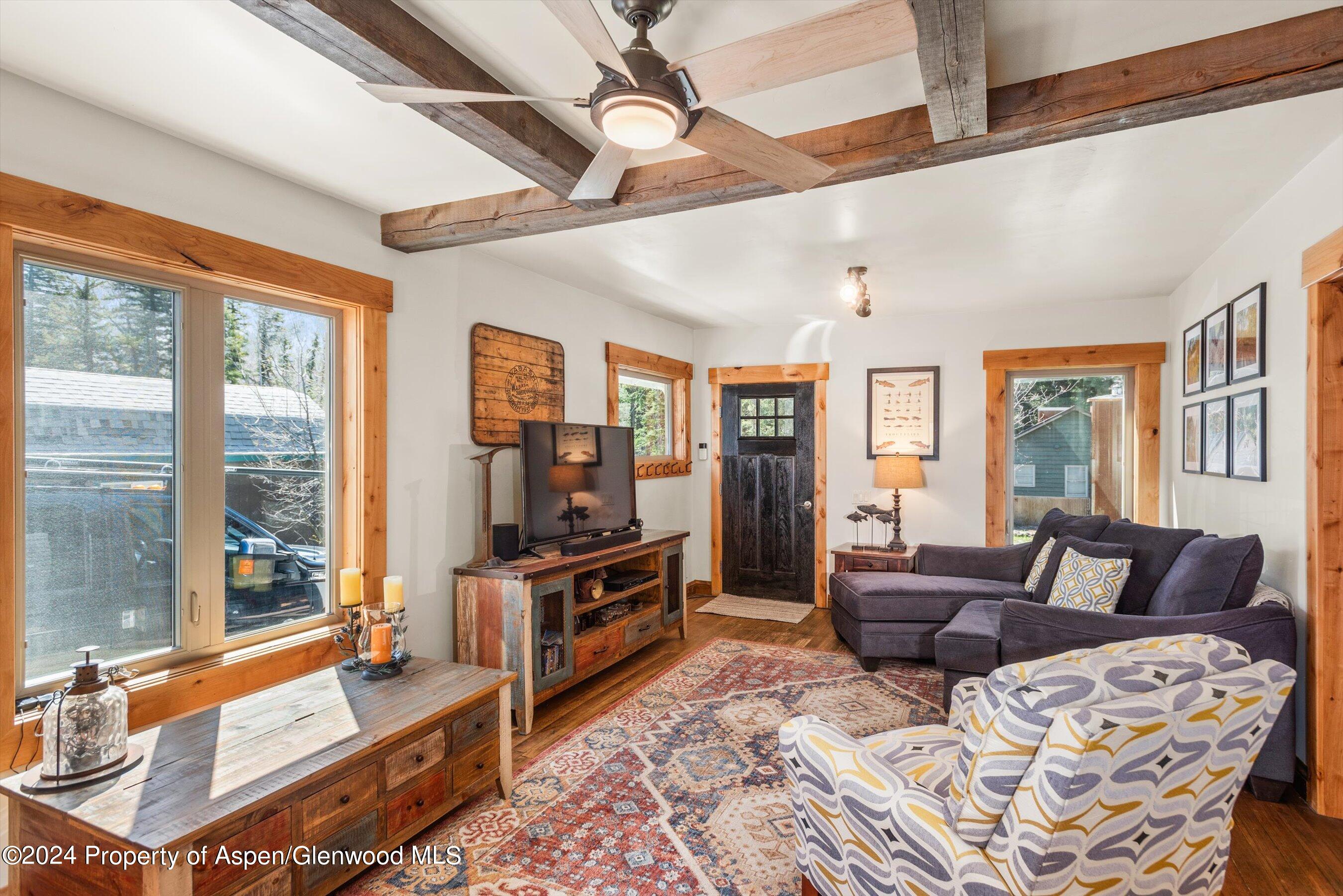 a living room with furniture a flat screen tv and large windows