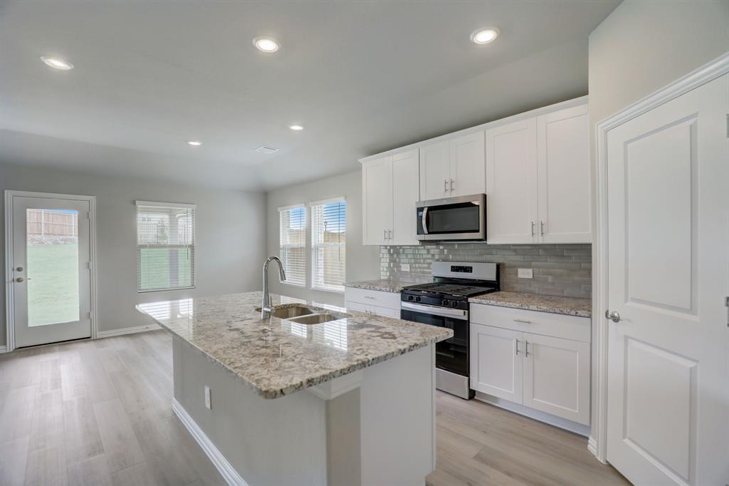 a kitchen with granite countertop white cabinets and stainless steel appliances