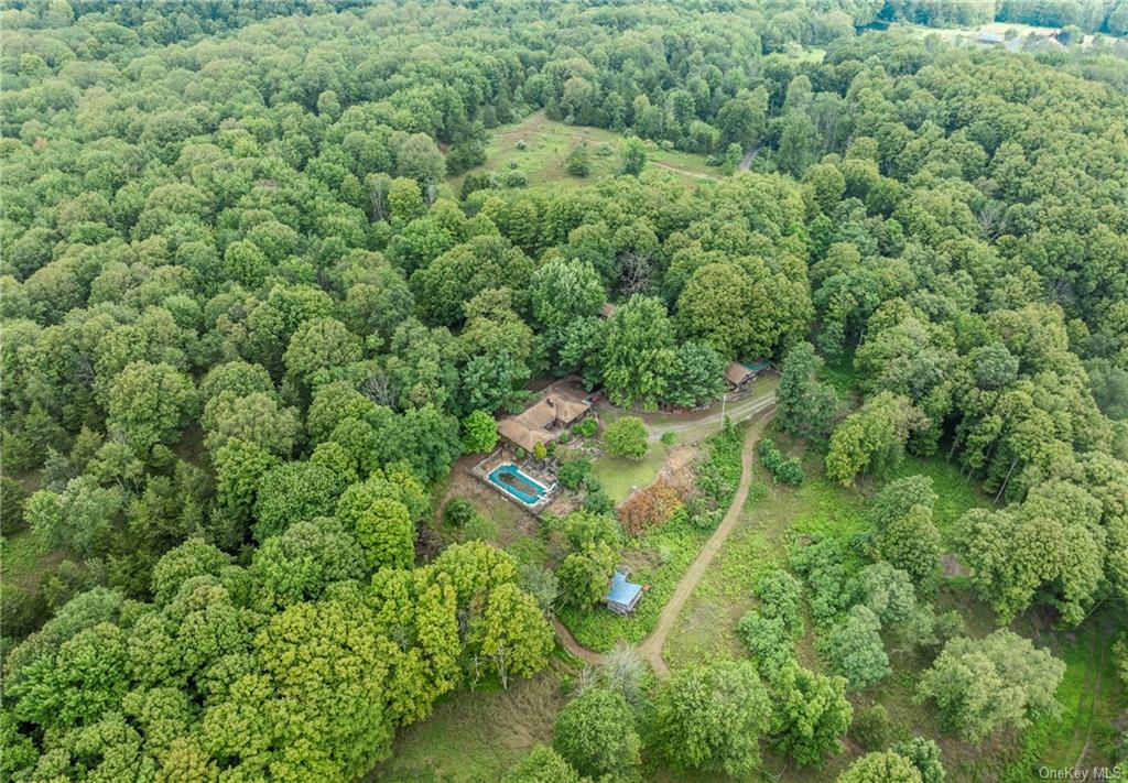 an aerial view of residential house with outdoor space and trees all around