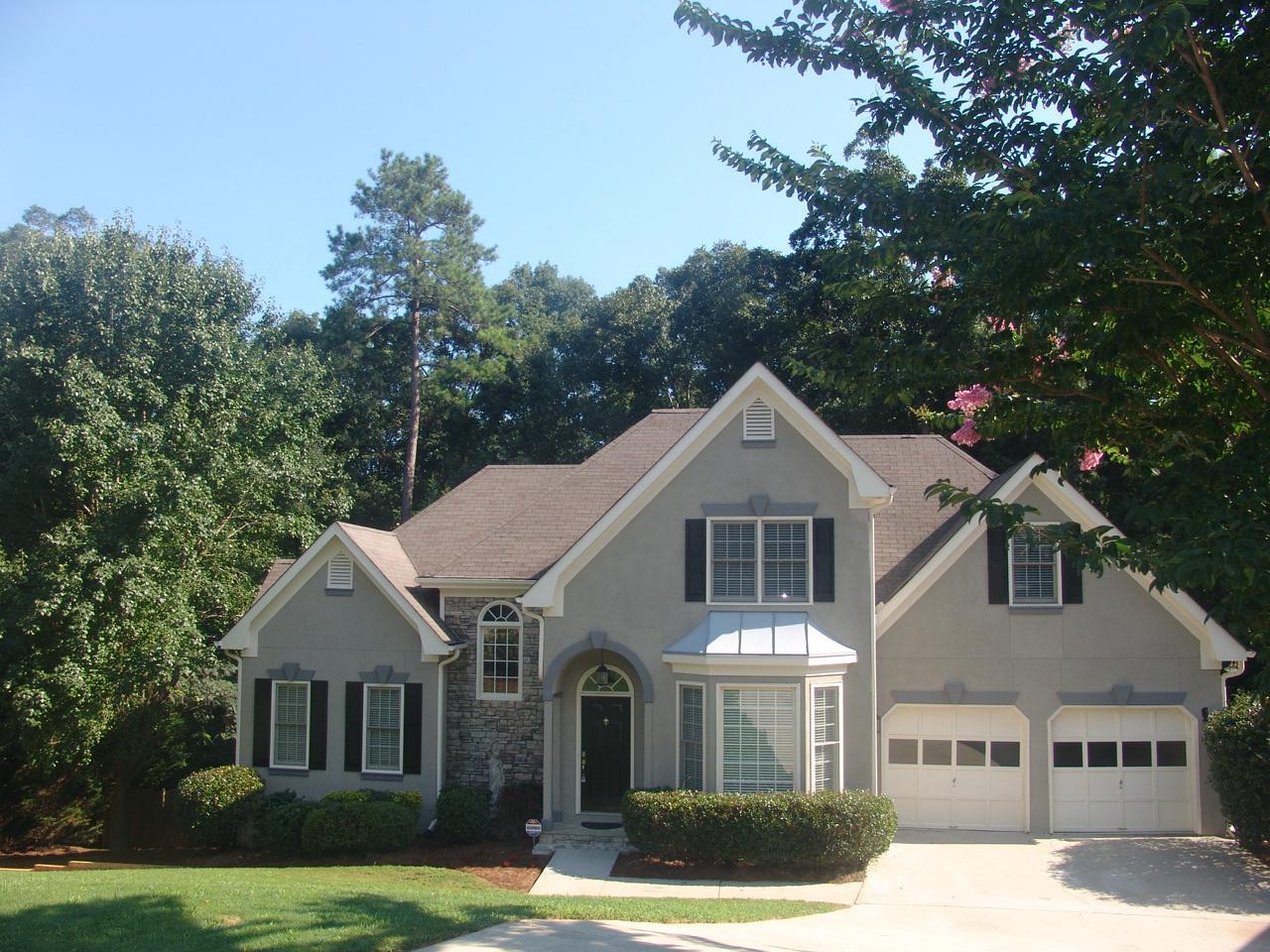 a front view of a house with a garden and trees