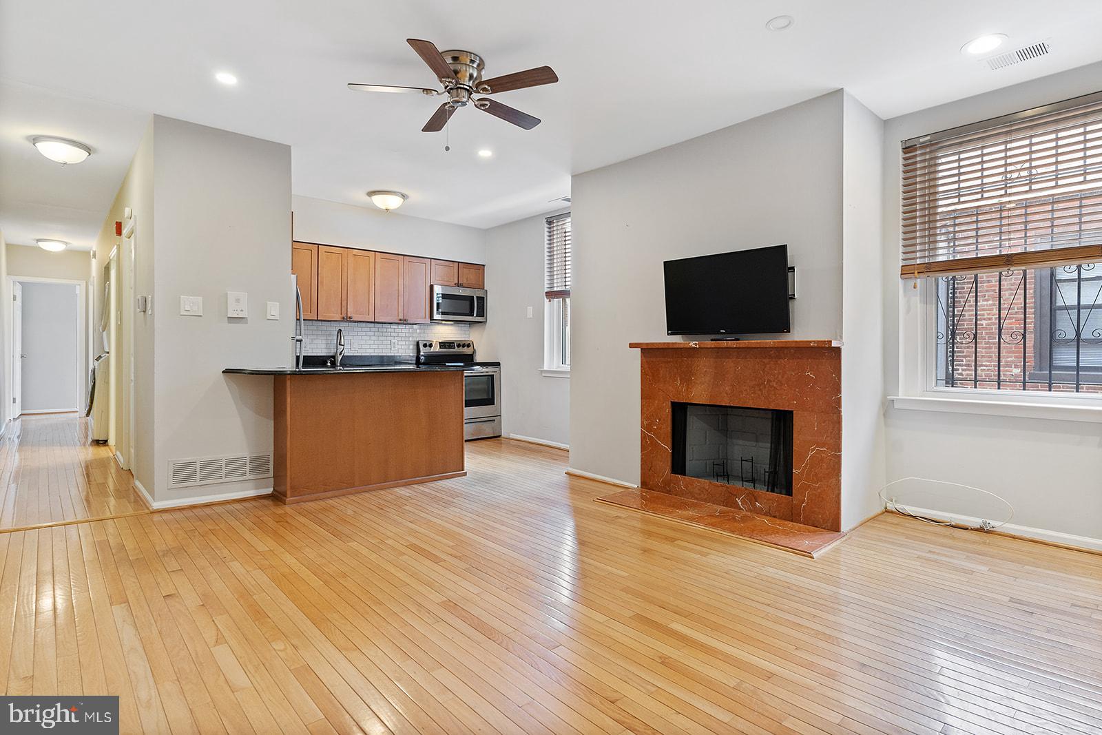 a view of a kitchen with a fireplace a ceiling fan and wooden floor