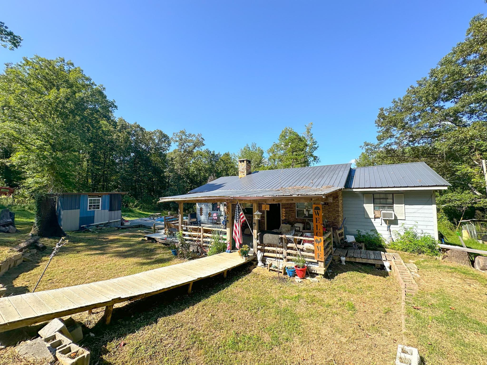 Exterior space featuring a storage unit, a wooden deck, and a front yard