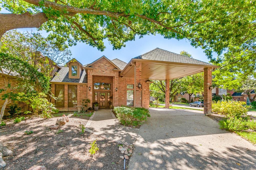 a view of a house with brick walls plants and large tree