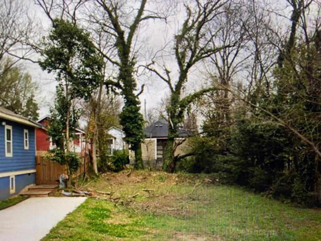 a backyard of a house with large trees and plants