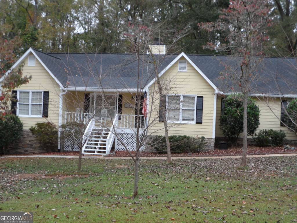 a view of a house with a yard and large trees