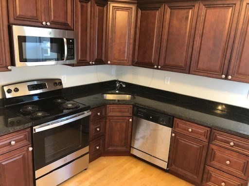 a kitchen with granite countertop wood cabinets stainless steel appliances and a sink