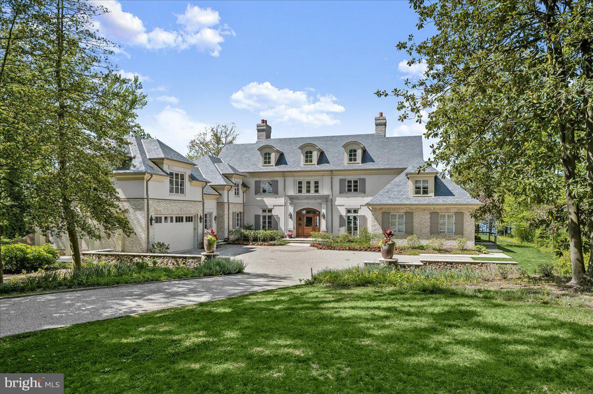 a view of a house with a big yard plants and large trees