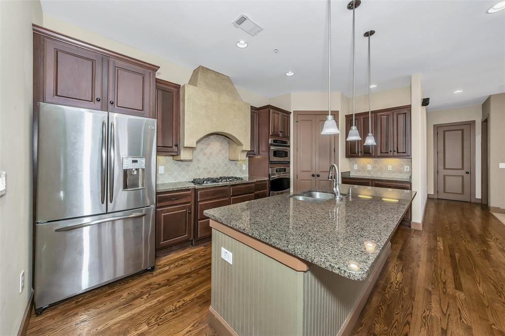 a kitchen with stainless steel appliances granite countertop a refrigerator a sink a stove and a wooden floors